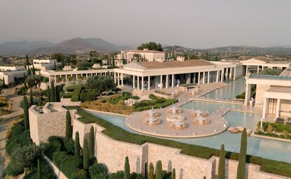 Aerial view of Amanzoe resort in Greece showing the main pavilion and manicured gardens with cypress trees.