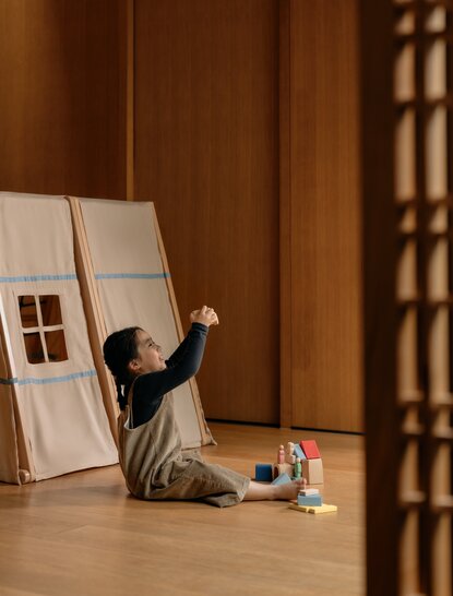 Child drawing on paper at Amanyangyun, wooden interiors in background.