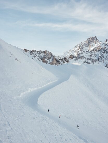 Skiers descend a snow-covered slope at Aman Le Mélézin in the French Alps.