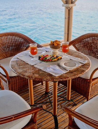 Floating bar at Amanpulo with woven chairs, table set with refreshments overlooking turquoise waters, Philippines.