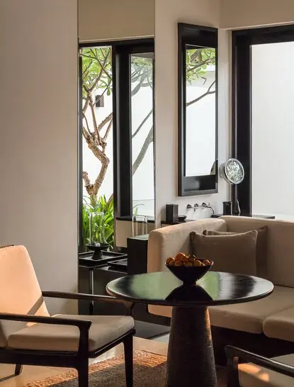 Suite living area with round table, chair, and garden views at Amansara, Cambodia.