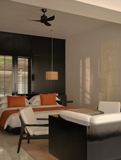 Amansara Suite interior with wooden desk, orange accents, and contemporary furnishings.