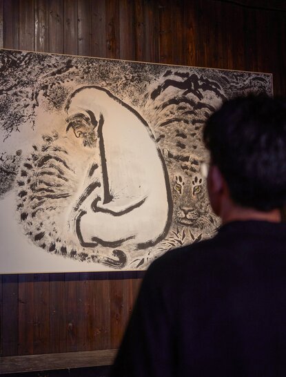 Artist's sketch displayed at Amanfayun exhibition, viewed by visitor from behind.