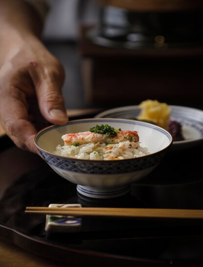 Hand serving bowl of soft-shell crab rice at Aman Kyoto.