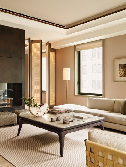 Corner Suite living room at Aman New York with seating area, wooden screens, and floor-to-ceiling windows.