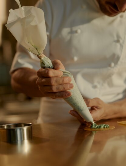 Hands kneading pasta dough at Aman New York's pasta-making experience.