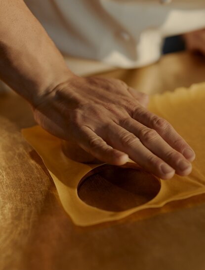 Hands shaping pasta dough at Aman New York's pasta-making experience.