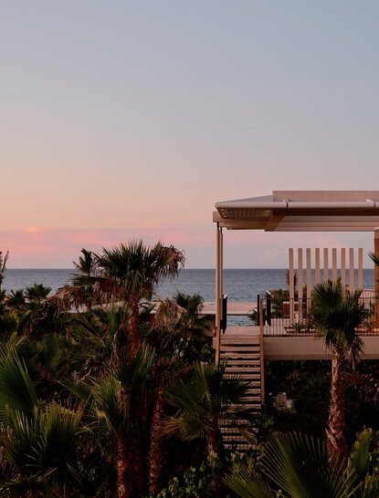 Horizon Casita at Amanvari with ocean view at dusk, framed by palm trees.