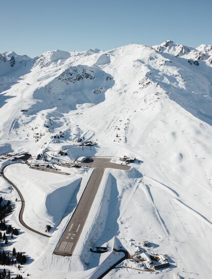 Aerial view of snow-covered Alpine peaks and Aman Le Mélézin resort nestled in the French mountains.