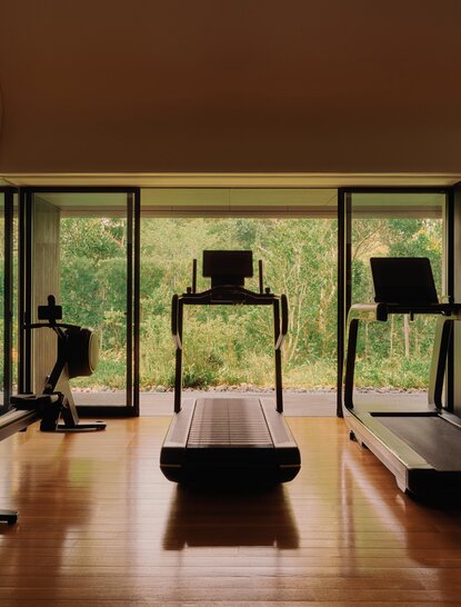 Amanemu spa and wellness studio with wooden flooring and floor-to-ceiling windows overlooking Japanese gardens.