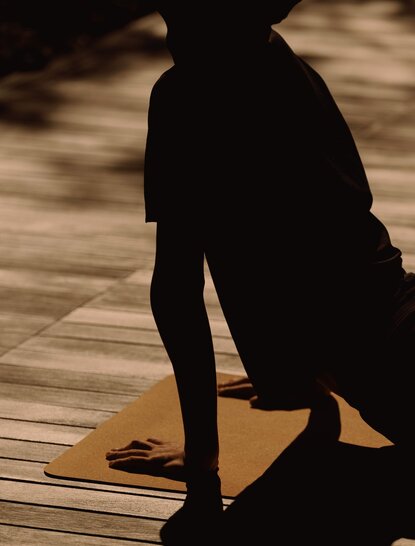 Silhouetted figure in yoga pose on wooden deck at Amanemu.