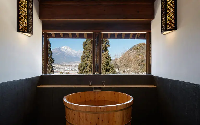 Wooden soaking tub overlooking mountain landscape at Amandayan wellness retreat.