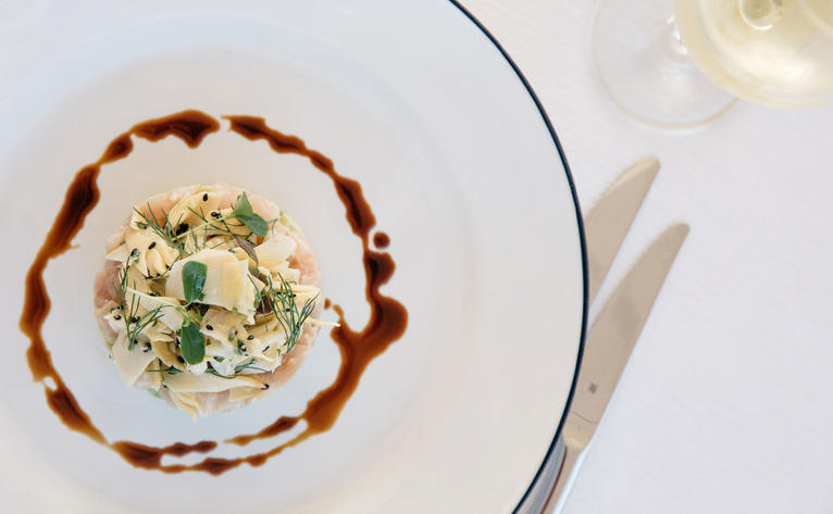 Artistic plated dish at Aman Sveti Stefan's Dining Arva, featuring creamy centre with herb garnish and decorative sauce border.