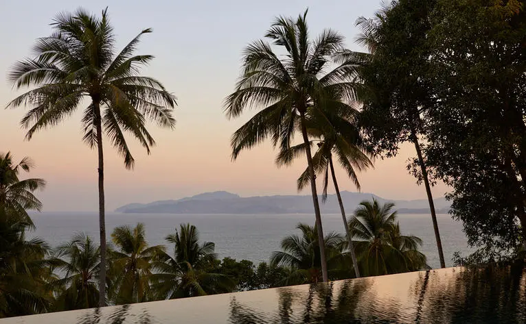 Amanpuri wellness overview: dawn light over tropical palms and distant coastline.