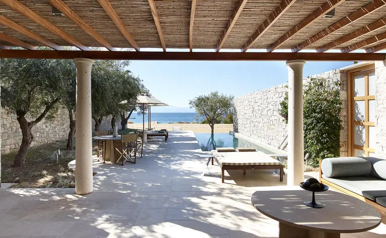 Beach Cabana at Amanzoe with shaded seating area overlooking Aegean Sea and olive trees.