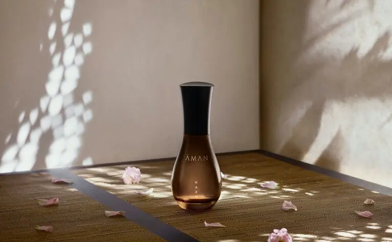 Flacon de parfum HARU d'Aman Fine Fragrance à Aman Tokyo, entouré de pétales de fleurs.