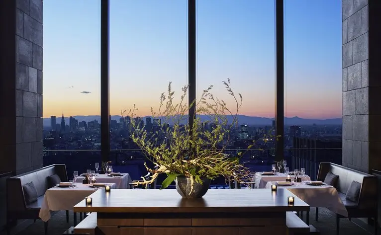 Dining table at Aman Tokyo with panoramic views of Tokyo's skyline at dusk.