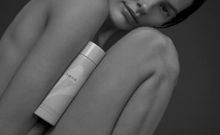 Aman Essentials skincare product displayed on bare shoulder at Aman Kyoto resort.
