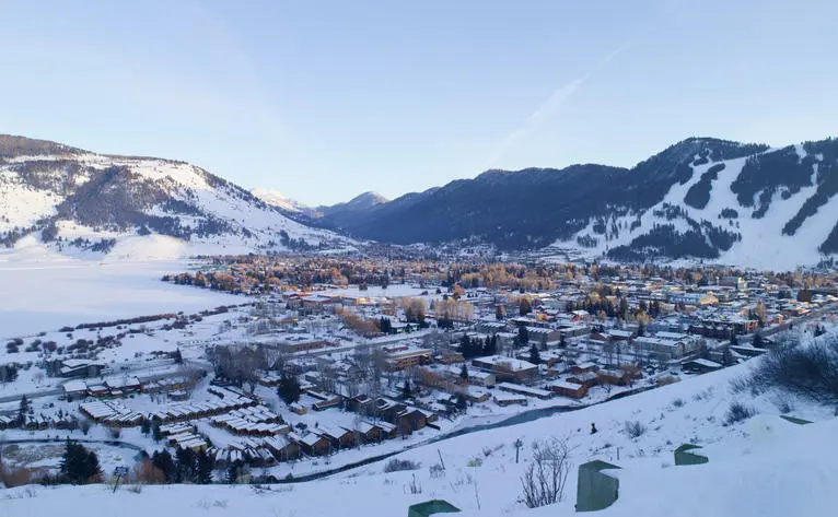 Amangani overlooks the snow-covered town of Jackson nestled in a winter valley below forested mountains.