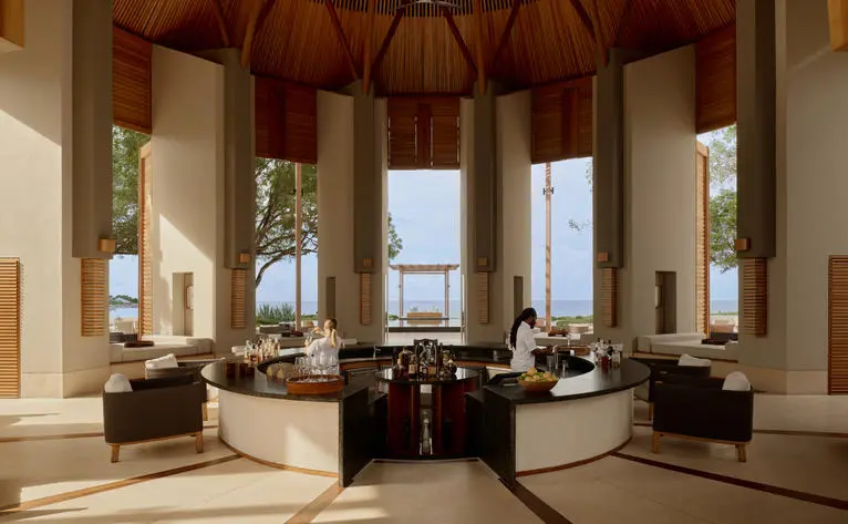 Bar at Amanyara resort with octagonal architecture, dark wood furnishings, and floor-to-ceiling windows overlooking the sea.