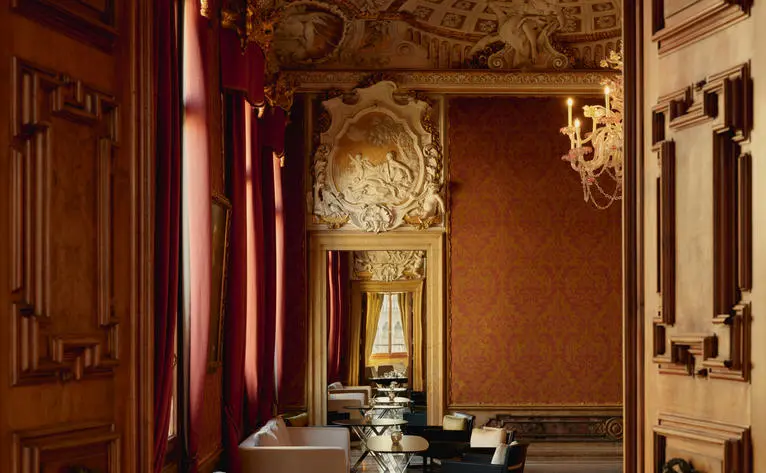 Bar dell'Aman Venice con pareti dorate, porte in legno e illuminazione calda.