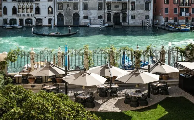 Terrazza da giardino con tavoli e ombrelloni affacciata sul Gran Canale a Aman Venice.