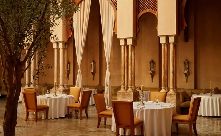 Restaurant marocain à Amanjena, avec tables rondes, colonnes en arche et décor ocre chaleureux.
