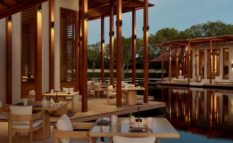 Restaurant principal d'Amanyara avec colonnes en bois et vue sur le lagon turquoise, à la station balnéaire.
