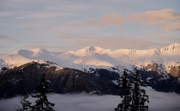 Snow-covered Alpine landscape at dusk with distant mountains at Aman Le Mélézin, France.