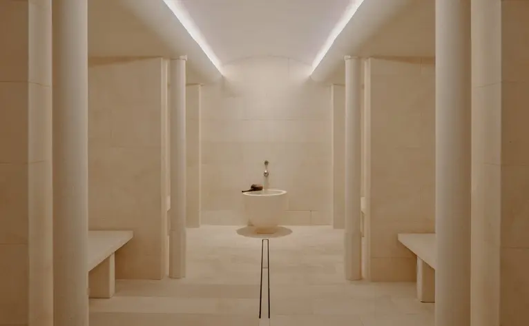Steam room at Aman Le Mélézin with symmetrical wooden panelling and soft overhead lighting.