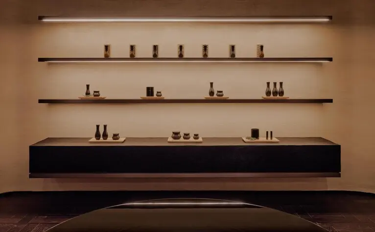 Aman Rosa Alpina resort spa display with minimalist shelving arrangement showcasing wellness products against a warm wall.