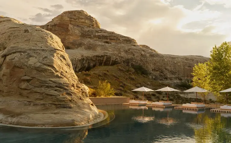 Amangiri's main pool reflecting towering rock formations under desert light.
