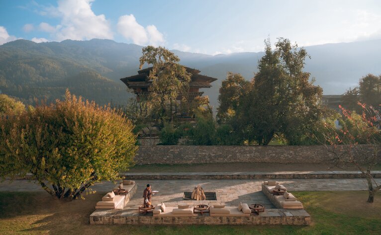 Firepit seating area at Amankora's Bumthang Lodge, surrounded by forested valleys in Bhutan.