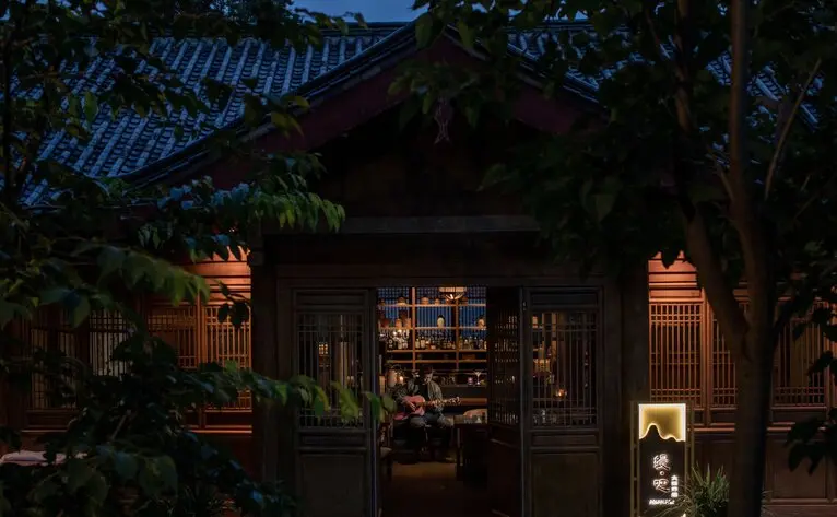 Tea house entrance at Amandayan, warmly lit exterior with traditional Chinese architecture at dusk.