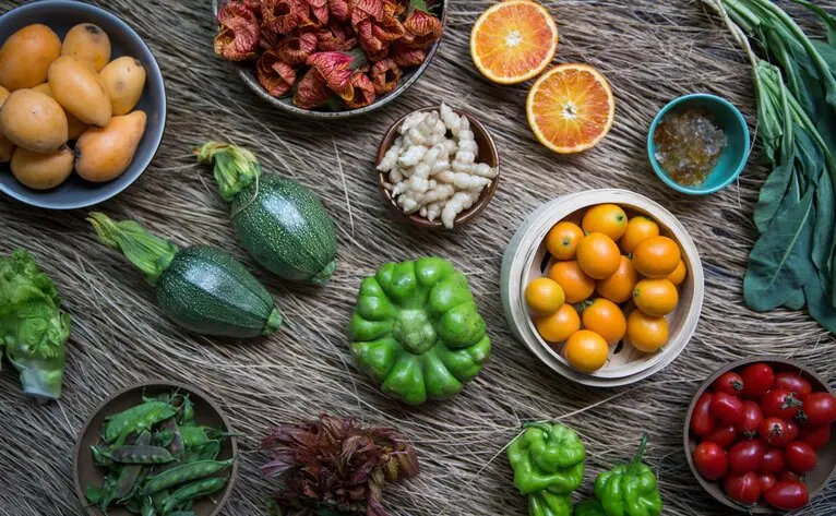 Amandayan spring menu ingredients: fresh vegetables, fruits and herbs arranged on a wooden surface.