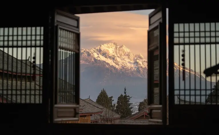 Snow-capped mountain framed by wooden doors at Amandayan, China's Man Yi Xuan Restaurant.