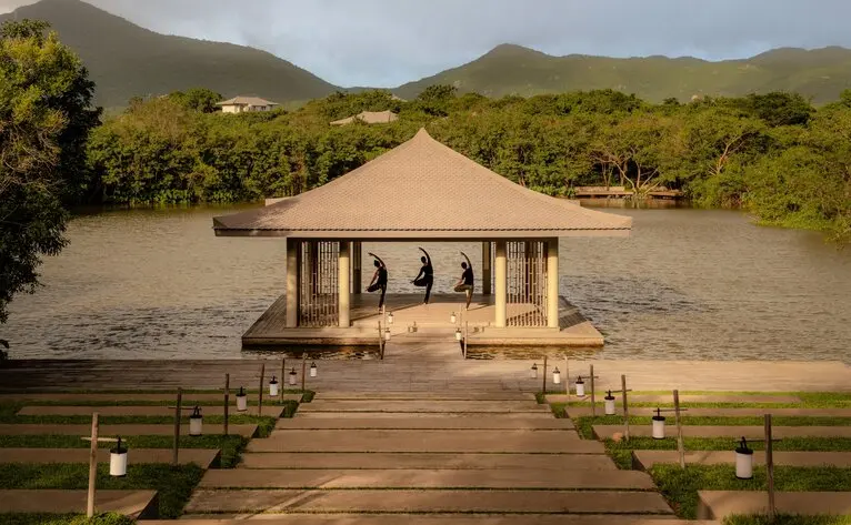 Yoga pavilion at Amanoi resort, with ochre canvas roof and wooden deck, set against verdant Vietnamese hillsides.