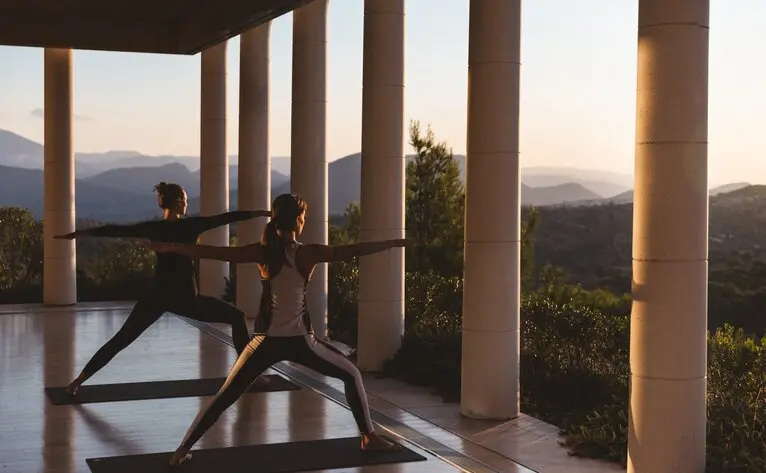 Sunrise yoga session on an open terrace at Amanzoe, overlooking Greek mountains and sea.