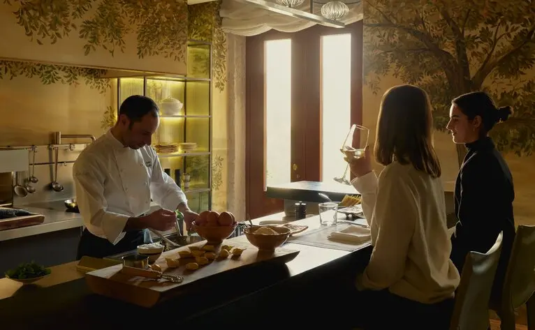 Palazzo Kitchen at Aman Venice, chef preparing dishes whilst visitors observe the culinary process.