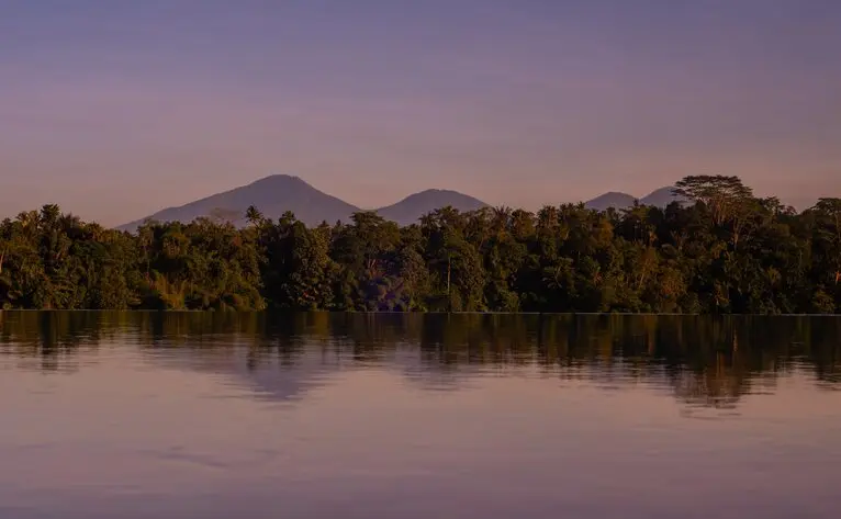 Amandari's pool reflects the forested landscape and distant mountains at dusk.