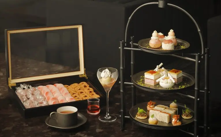 Aman Tokyo Lounge: peach-toned decorative display with laptop, tiered stand, and refreshments.