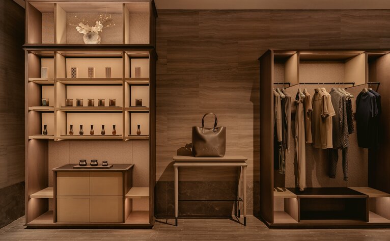 Wooden wardrobe display at Aman Nai Lert Bangkok showing shelving, folded clothing and hanging garments.