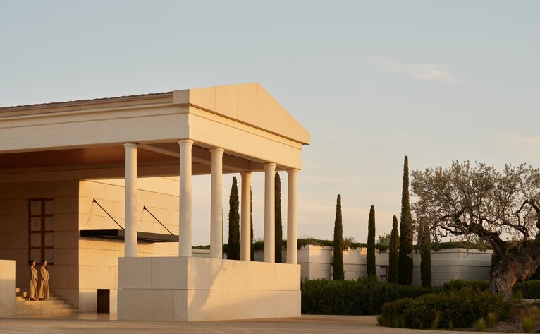Amanzoe resort arrival pavilion with golden-hour architecture and cypress trees, Greece.