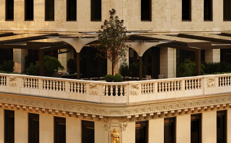 Garden terrace at Aman New York with classical architecture and potted greenery.