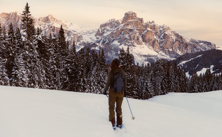 Skier touring through snow-covered Alpine landscape near Aman Rosa Alpina, Italy.