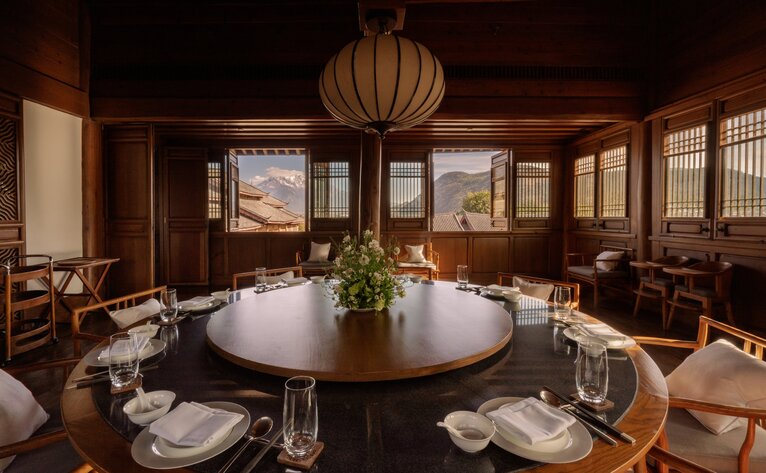 Private dining room at Amandayan with round table set for service, warm wood panelling, and pendant lighting.