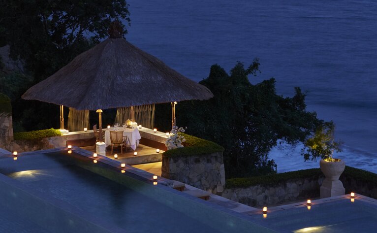 Salle à manger Bhoga illuminée au crépuscule à Amankila, resort en bord de mer.