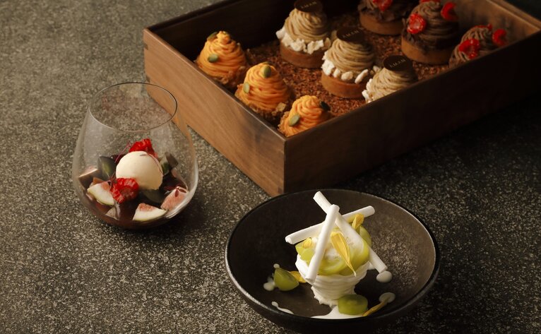 Assorted pastries in wooden box with individual desserts at Aman Tokyo café.