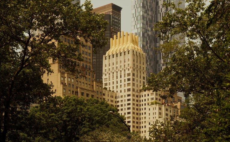 Art Deco skyscraper framed by autumn foliage at Aman New York hotel.