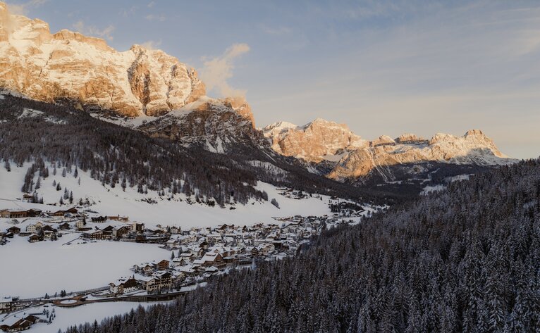 Mountain valley with snow-covered peaks and forested slopes at Aman Rosa Alpina, Italy.
